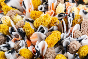 Close up shot of a Henry & Sadie Snuffle Mat made of Orange, White, Black Fleece and Yellow and Beige Yarn