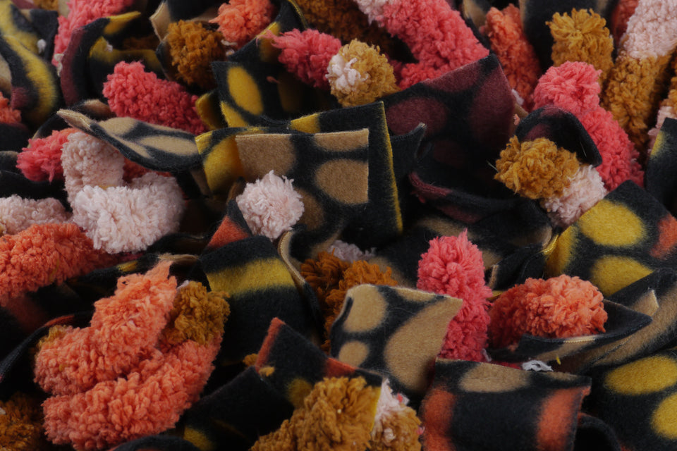 Henry & Sadie Snuffle mat in orange and pink yarn and yellow, brown, and Black Fleece