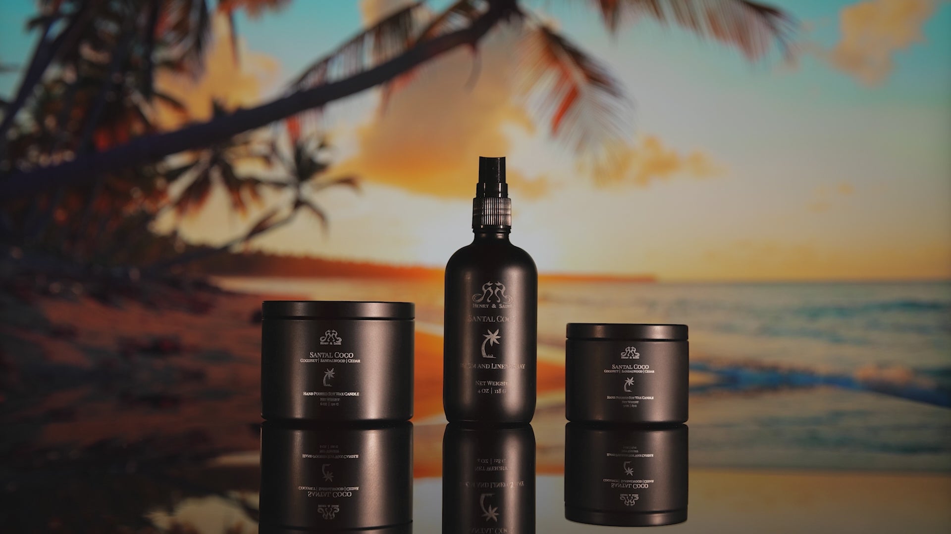 Video showing a tropical island with coconut trees, sunset, and blue ocean waves showcasing the Henry and Sadie Santal Coco Room Spray and candles in black containers sitting on a reflective surface